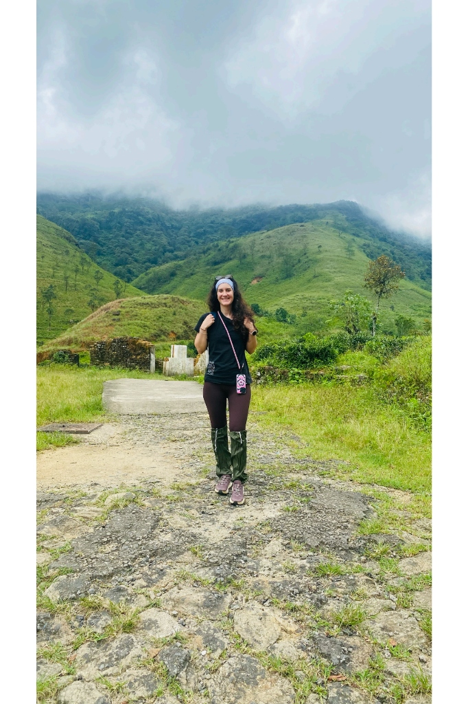 Smiling hiker walking along a mountain stone path through lush green Knuckles valleys with misty peaks in the background