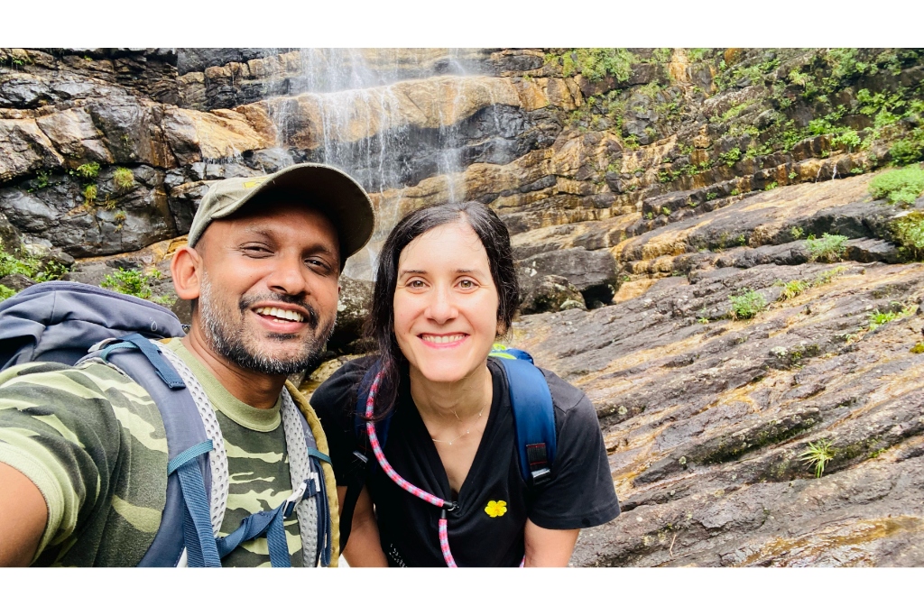 Guide Ravi and a smiling trekker pausing for a close-up photo in front of a cascading mountain waterfall in Knuckles