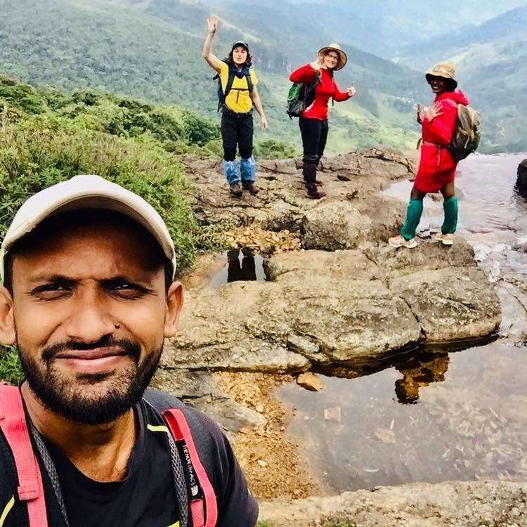Guide Ravi taking a selfie with three hikers on a rocky Knuckles mountain trail above scenic valleys