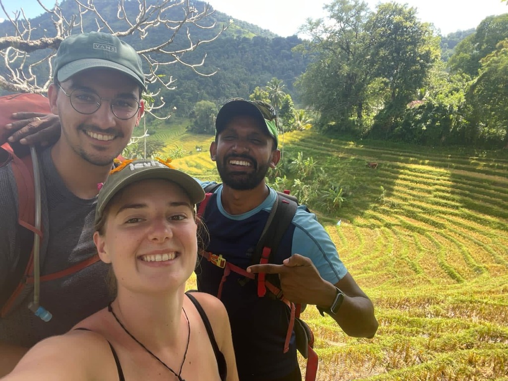 Guide Ravi and trekkers pausing on a trail overlooking scenic terraced rice fields in the Knuckles