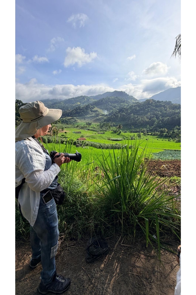 Adventure trekker with a camera overlooking lush green terraced rice fields and mountain valleys in Knuckles